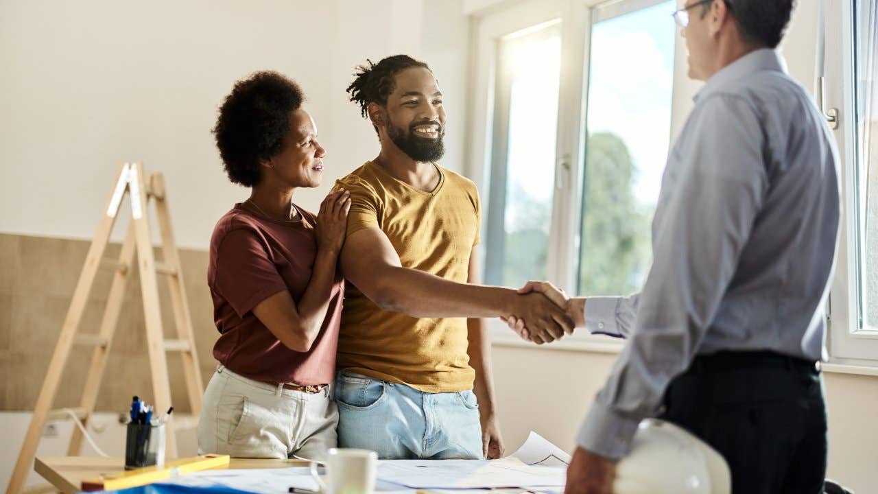 Happy black couple shaking hands with a homebuilder
