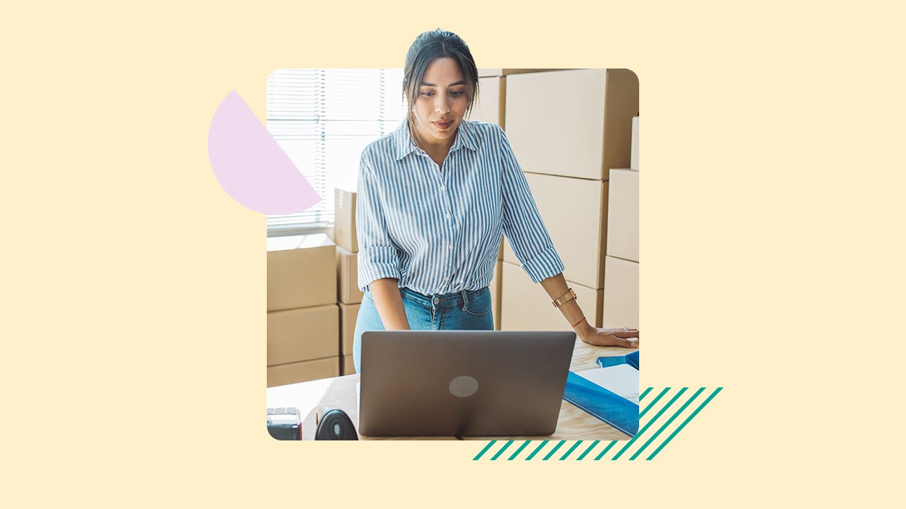 A small business owner stands while working on her laptop.