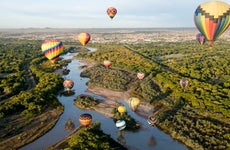 Hot air balloons drifting over the Rio Grande river in Albuquerque, New Mexico.