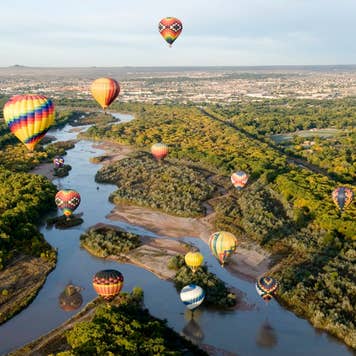 Hot air balloons drifting over the Rio Grande river in Albuquerque, New Mexico.