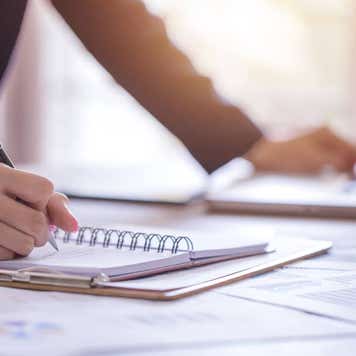 woman writing down financial information on a notepad