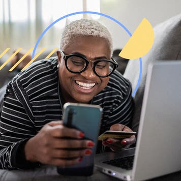 Person holding credit card while working on a laptop