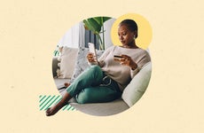 design image of a woman sitting on her couch and looking at a phone in her hand and a credit card in the other