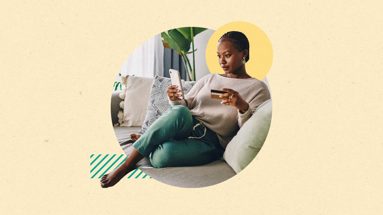 design image of a woman sitting on her couch and looking at a phone in her hand and a credit card in the other