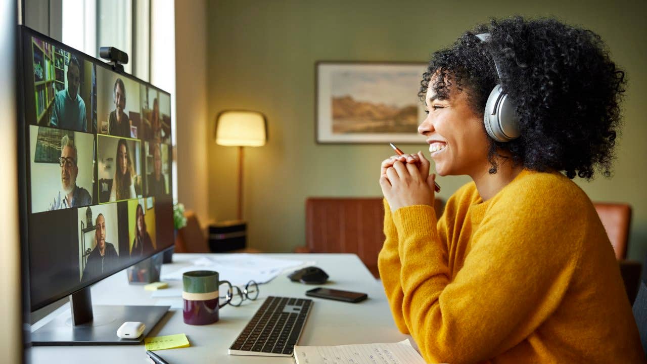 Businesswoman with headphones smiling during video conference. Multiracial male and female professionals are attending online meeting. They are discussing business strategy.