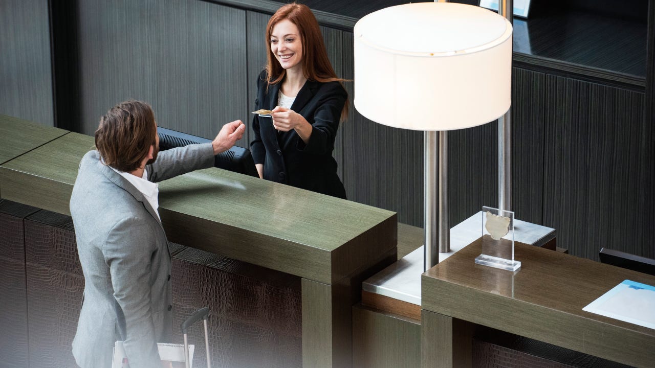 Smiling female receptionist giving credit card to businessman while standing at hotel reception
