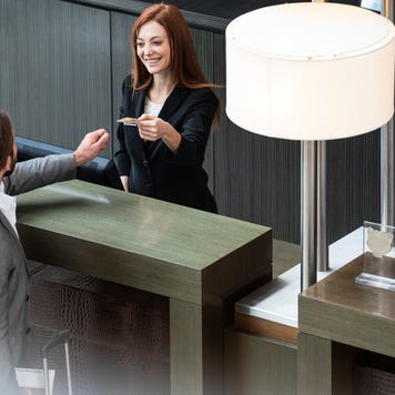 Smiling female receptionist giving credit card to businessman while standing at hotel reception