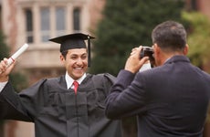 College graduate in cap and gown with diploma