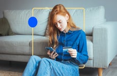 design element of an image of a woman sitting in front of a couch holding a phone in one hand and credit card in the other