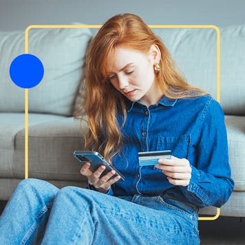 design element of an image of a woman sitting in front of a couch holding a phone in one hand and credit card in the other