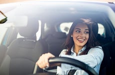 happy brunette woman is driving a car