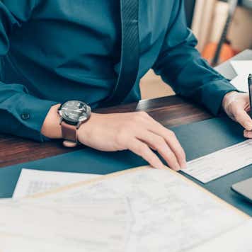 Business man hand writing and signing white blank bank check book