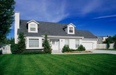 large white suburban home with green lawn and blue sky