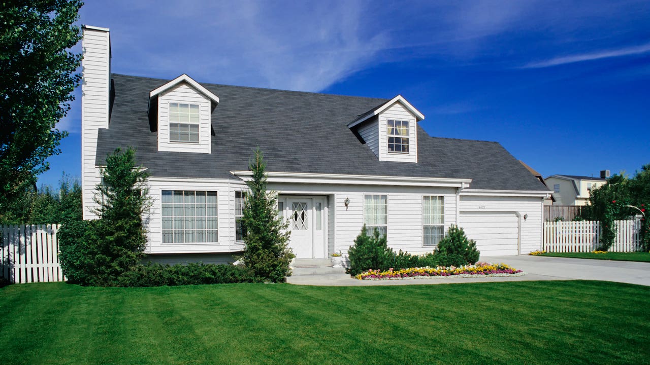 large white suburban home with green lawn and blue sky