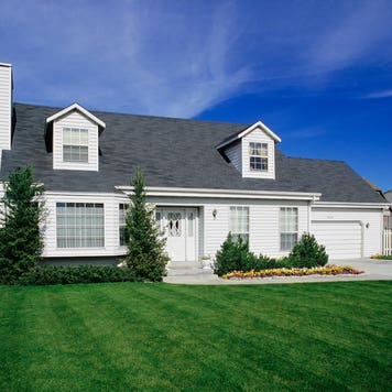 large white suburban home with green lawn and blue sky