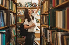 Portrait of female student looking for special book