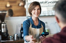 A barista accepts a credit card from a customer.