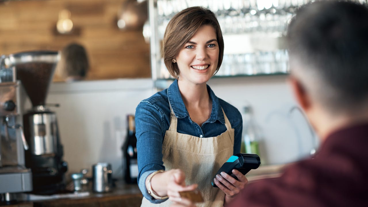 A barista accepts a credit card from a customer.