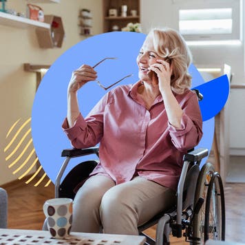 An older white woman sits in a wheelchair while talking on the phone.