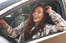 Young smiling woman driving a car in the city