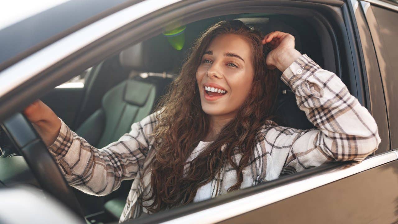 Young smiling woman driving a car in the city