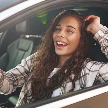 Young smiling woman driving a car in the city