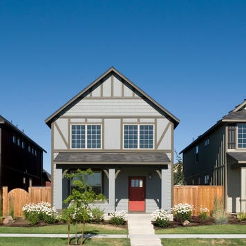 three modest suburban homes with front porches and blue sky