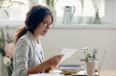 Focused young woman reading paper letter at work desk