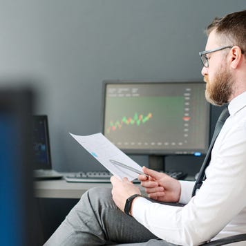 Young adult man with beard on face sitting at desk in office working on investment business strategy