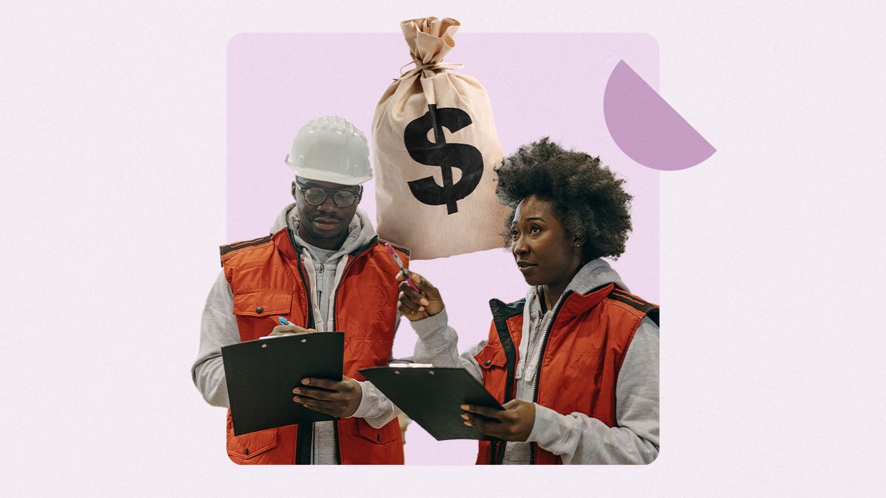 Black man and woman standing, holding clipboards in construction vests.
