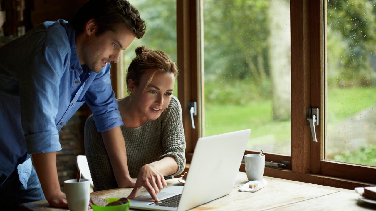 Young couple using laptop at table in cottage