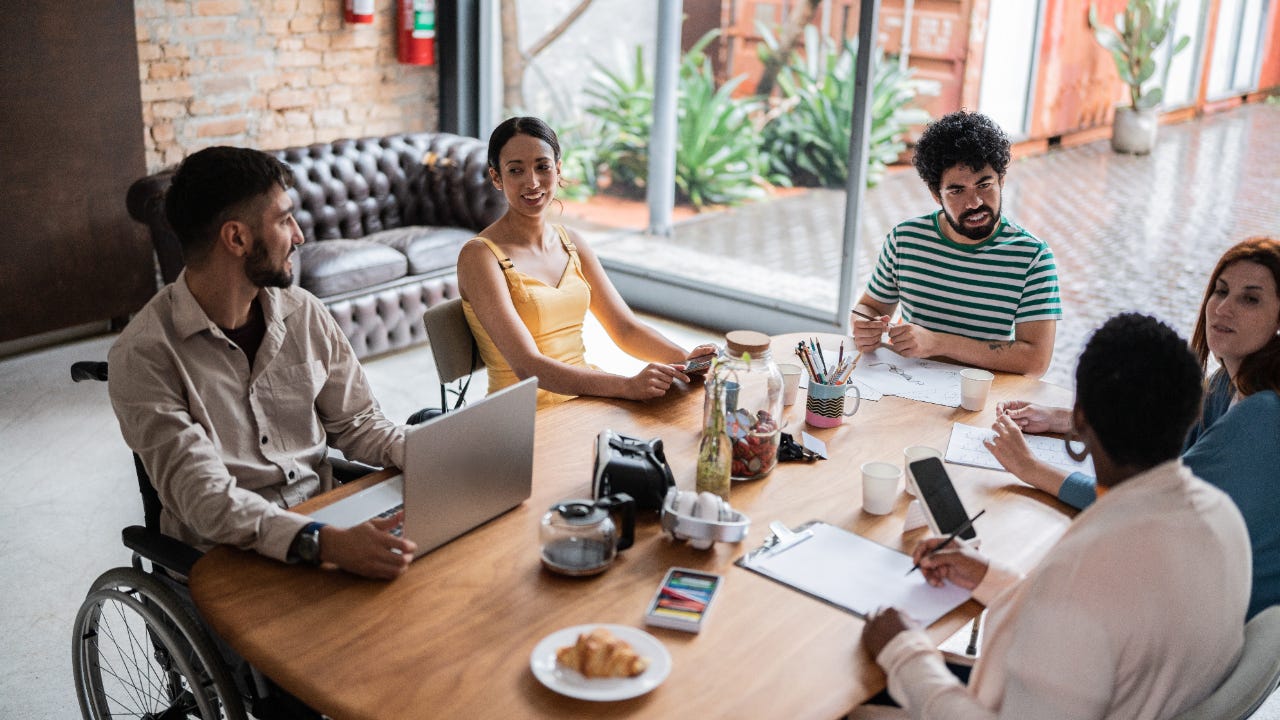 Five people sit around a table discussing business.