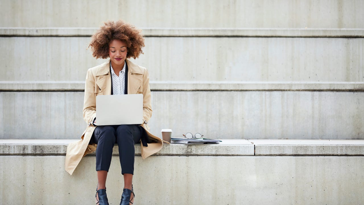 Young businesswoman using laptop while sitting on steps