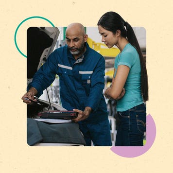A young Asian woman and a Black mechanic look at the engine of a car.