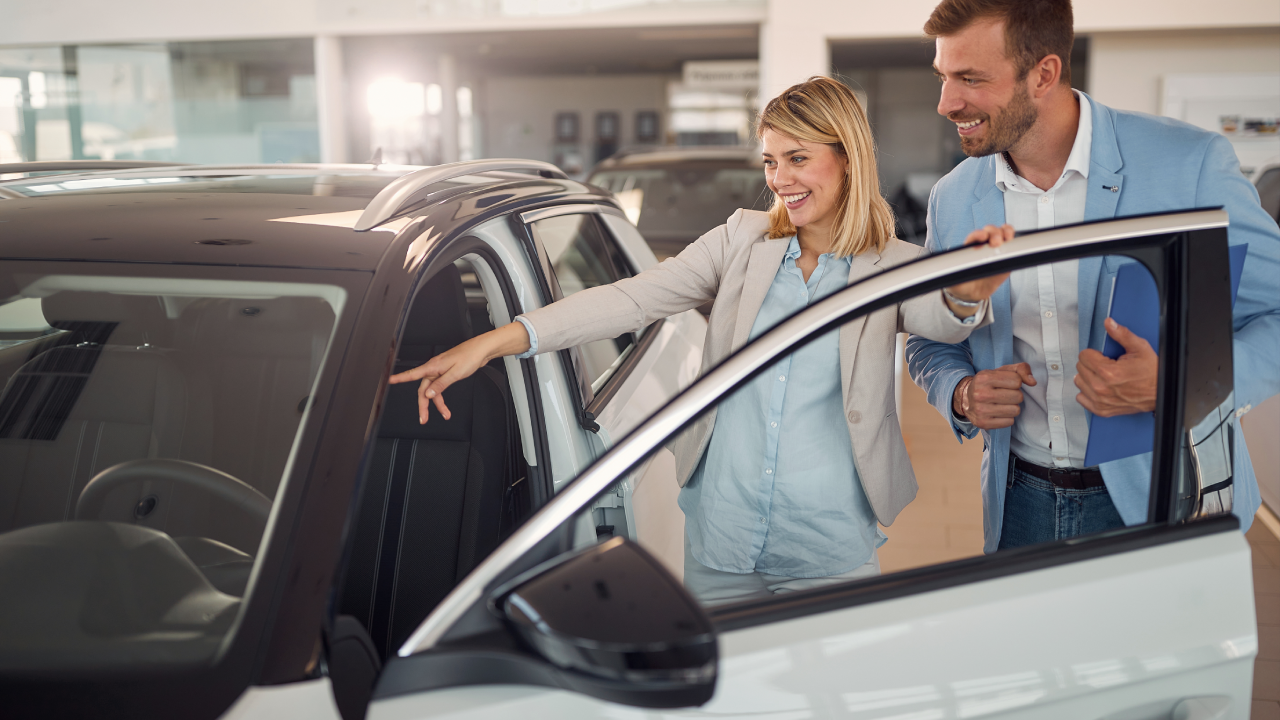 Smiling woman in the car dealership buying car