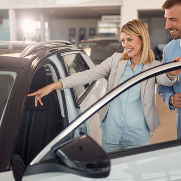 Smiling woman in the car dealership buying car