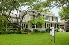 view of residential home with for sale sign on the large green front lawn