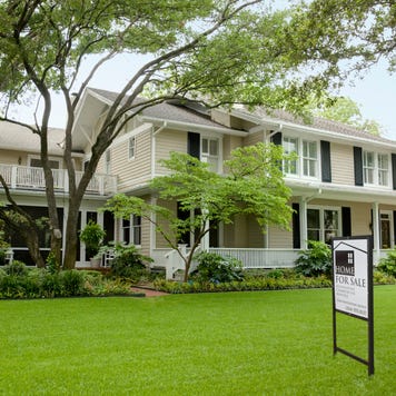 view of residential home with for sale sign on the large green front lawn