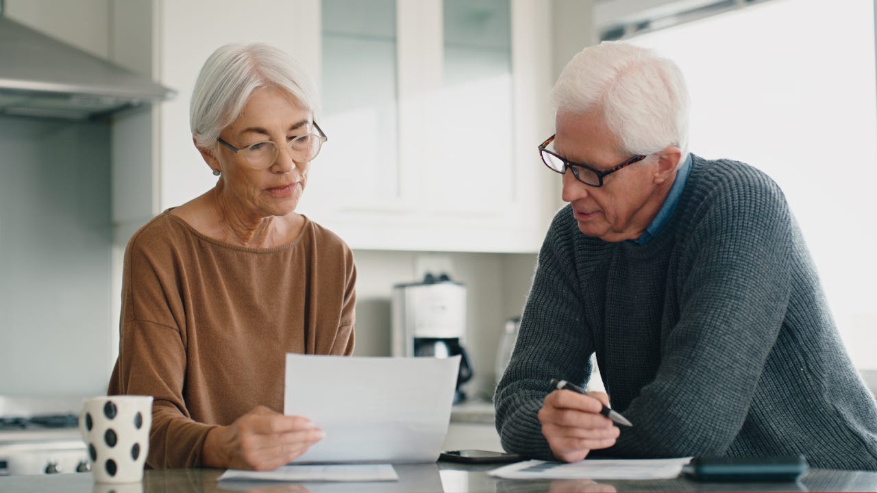 Older couple reading financial documents in their kitchen