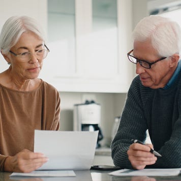 Older couple reading financial documents in their kitchen