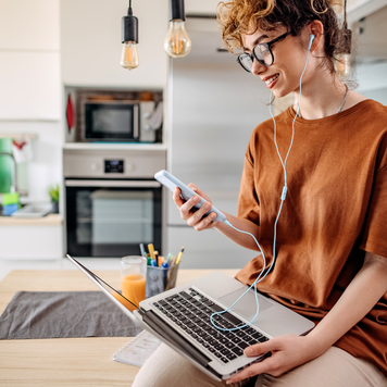 young white woman with red hair working on laptop in kitchen
