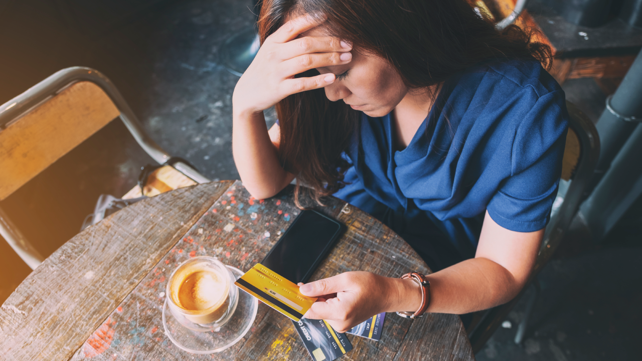 adult women looking at her credit card with one hand on her foerhead