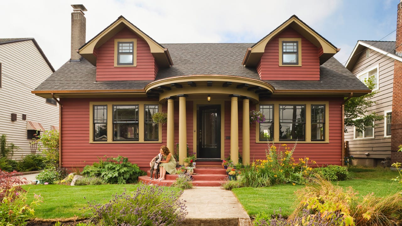 Woman & dog sitting on the porch of a quaint house