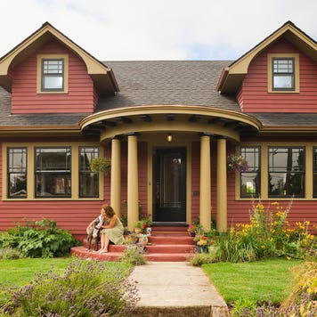 Woman & dog sitting on the porch of a quaint house