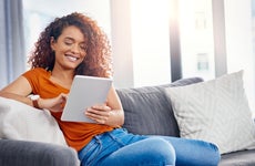 young woman using a digital tablet on the sofa at home