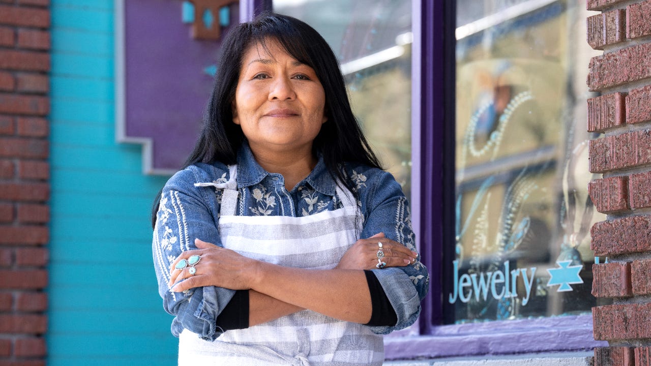 Native American woman stands in front of her small business.