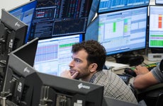 A stock trader follows the price development on his monitors in a trading room