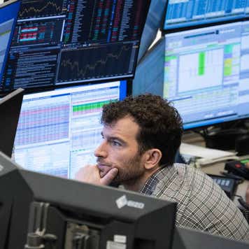 A stock trader follows the price development on his monitors in a trading room