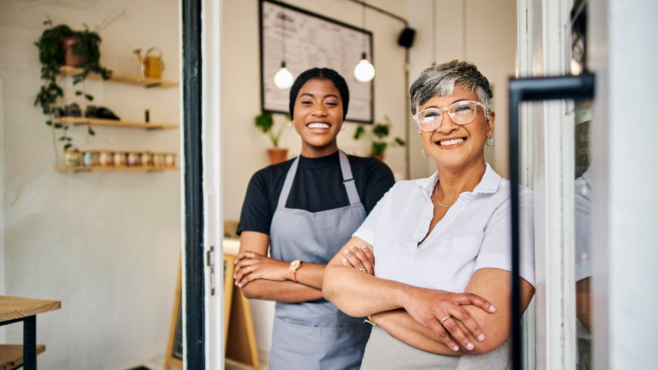 An older and younger woman stand in the doorway of a shop