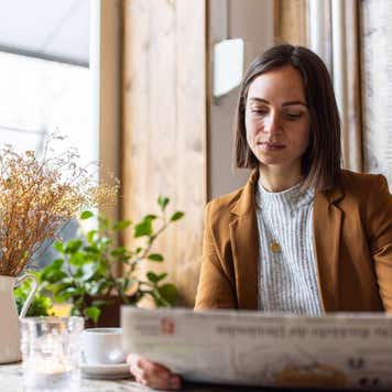 Businesswoman reading newspaper in cafe